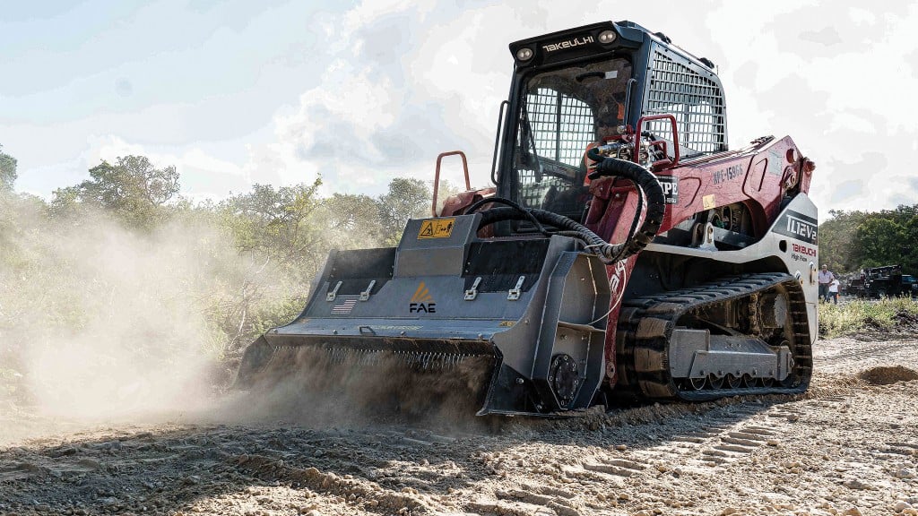 A skid-steer loader with a rock crushing attachment operates on a job site