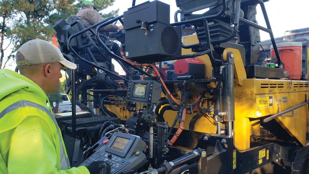 An operator uses machine control on a paver