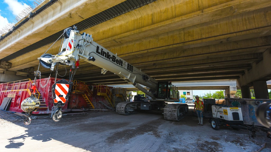 A crawler crane travels underneath a bridge