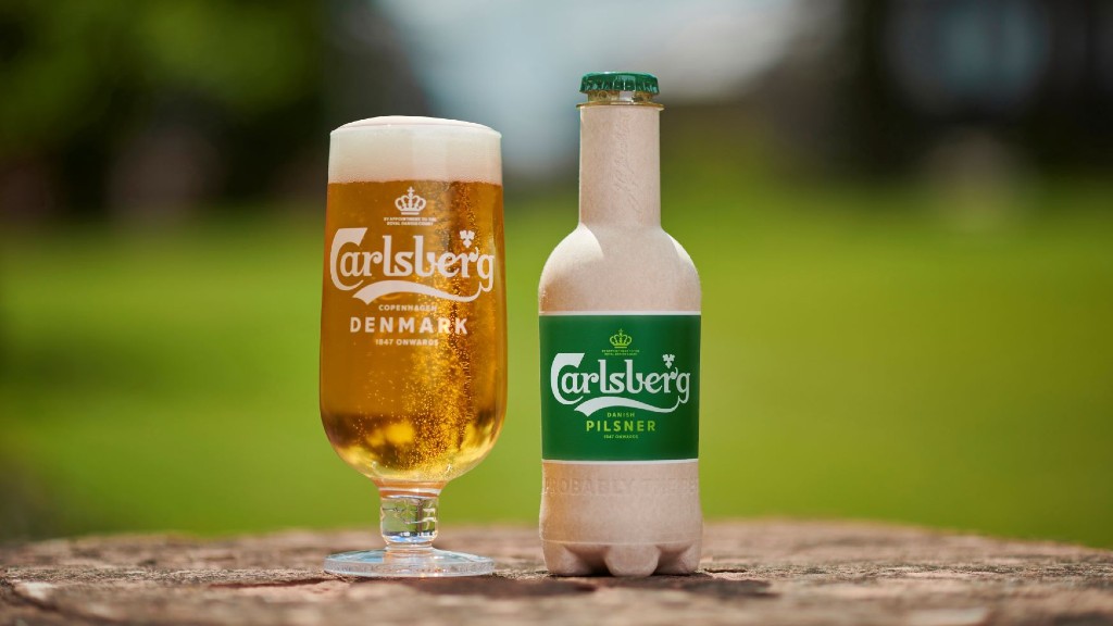 A fibre beer bottle and a sleeve of beer are placed on a stump