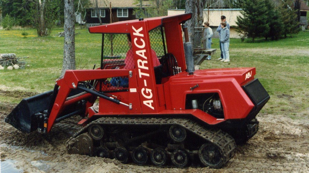 A compact track loader moves along a dirt path on a job site