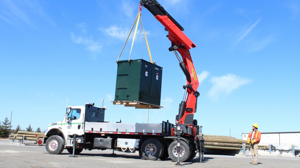 A truck crane operates on a road side