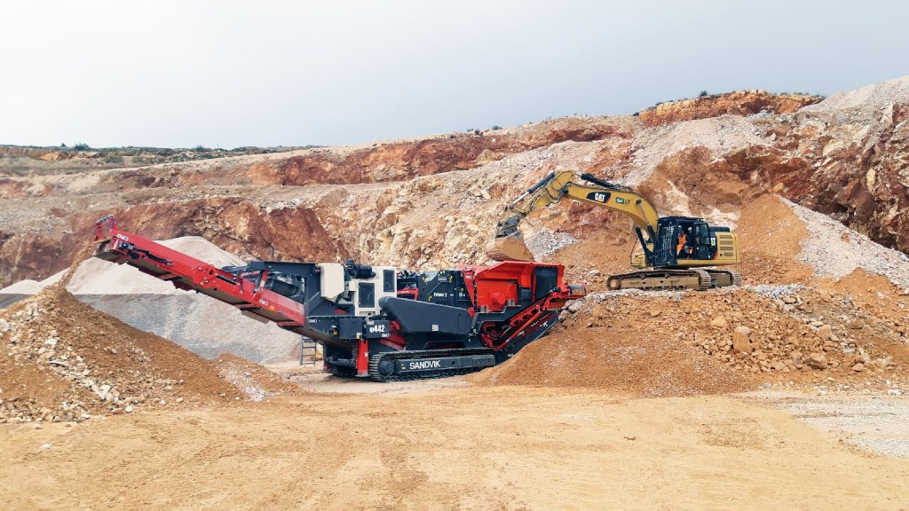 An excavator fills a mobile crusher on a job site