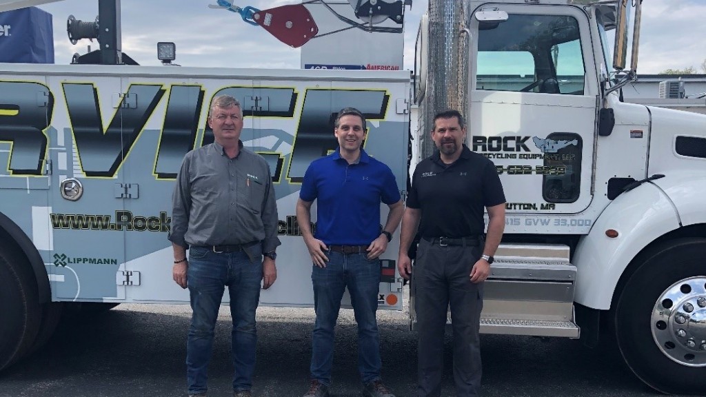 Several people pose for a photo near a truck