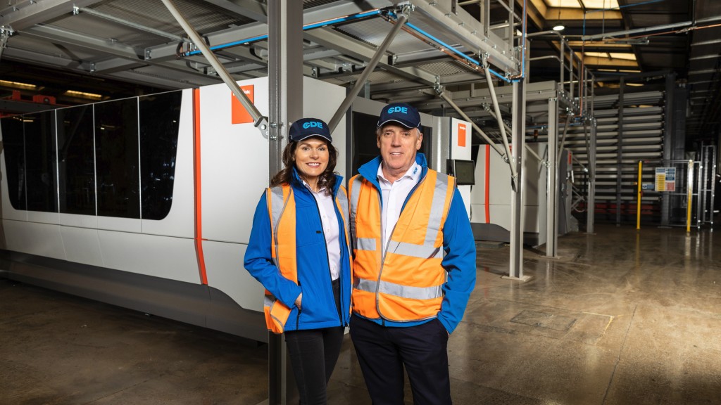 Two people in safety vests stand inside a building