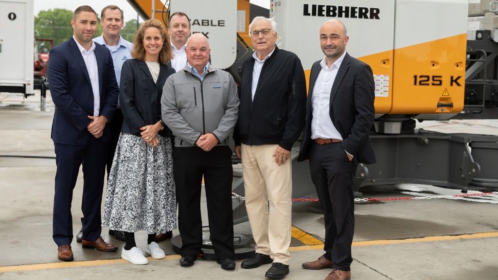 A group of people stand in front of a tower crane