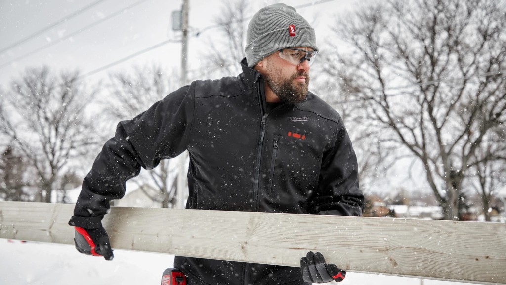 A worker carries a wooden board on a snowy job site