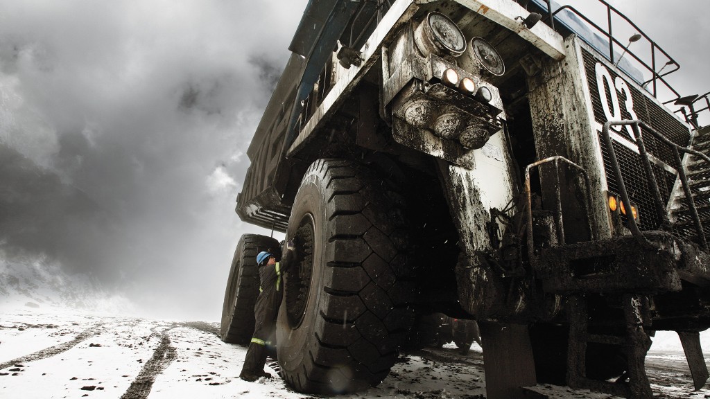 A worker performs maintenance on a tire on a job site