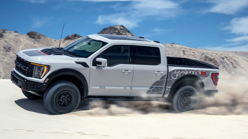 A truck drives on a dune of sand