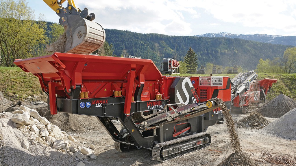 An excavator puts rock material into an aggregate equipment line