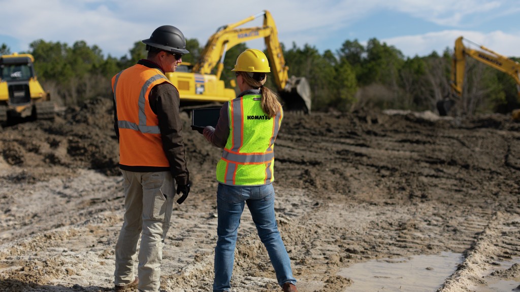 Two workers look at a tablet on a job site