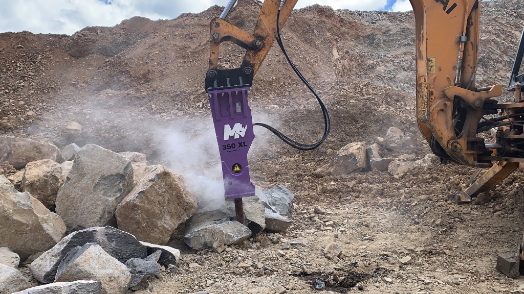 A hydraulic breaker breaks down a rock on a job site