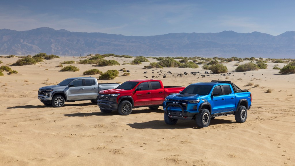 Several pickup trucks are parked in a desert