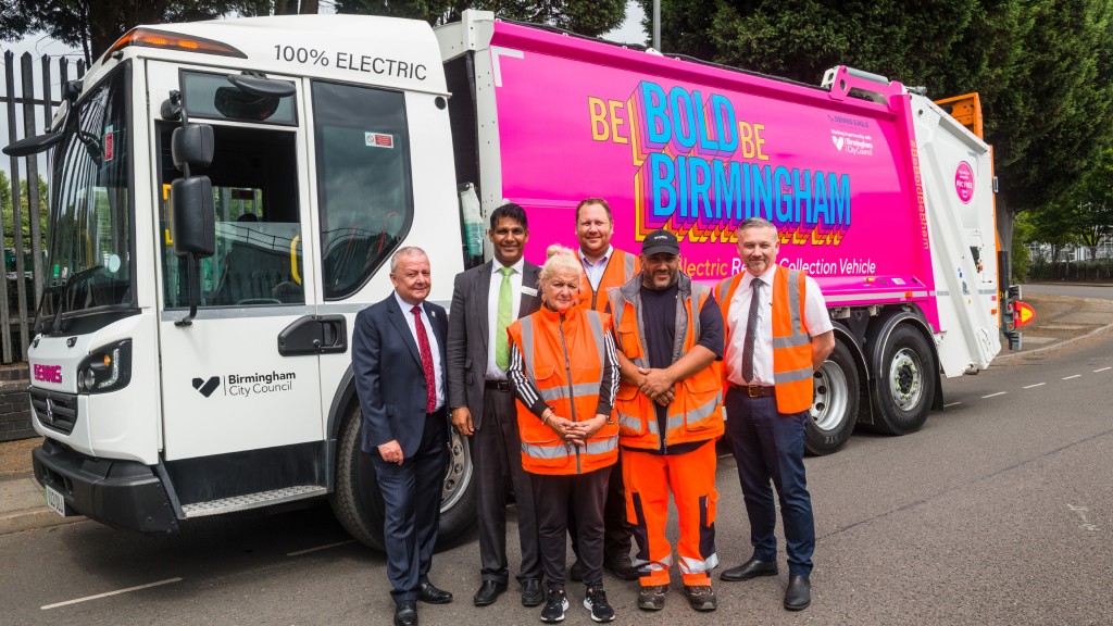 Several people pose for a photo in front of a collection truck