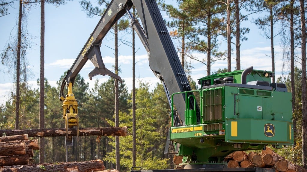 A knuckleboom loader moves logs on the job site