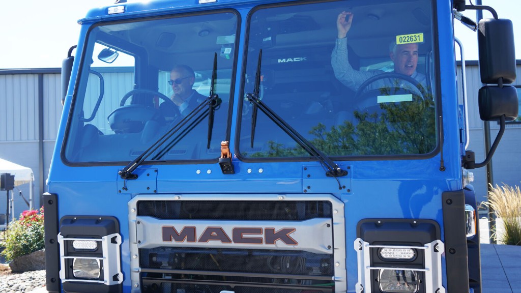 Two people sit in the cab of an electric collection truck