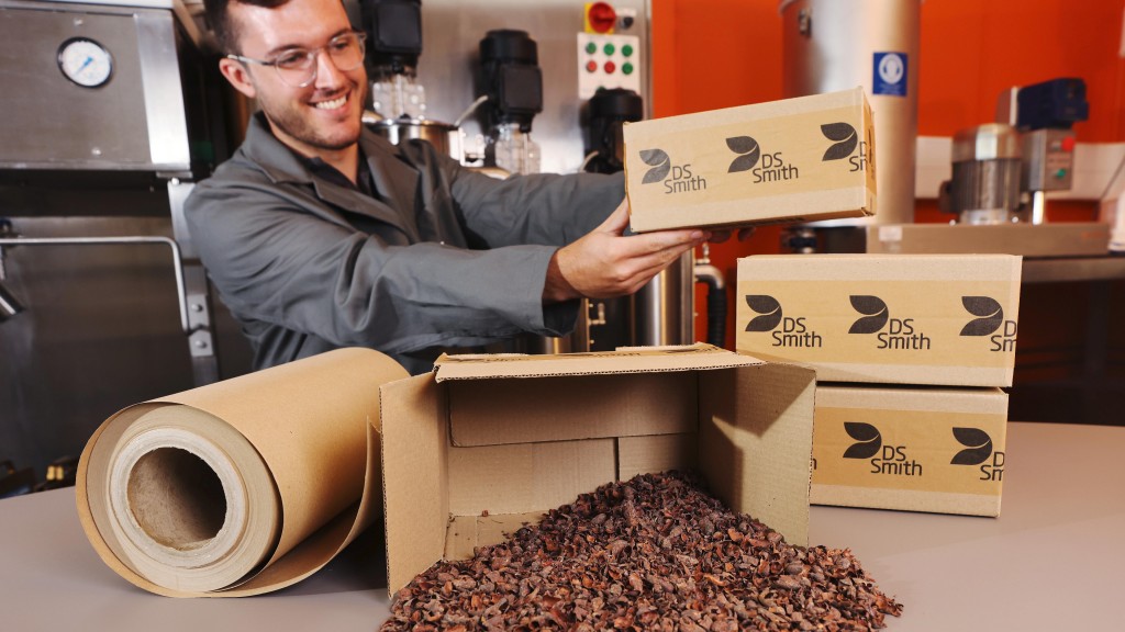 Somebody holds a cardboard box made from cocoa shells