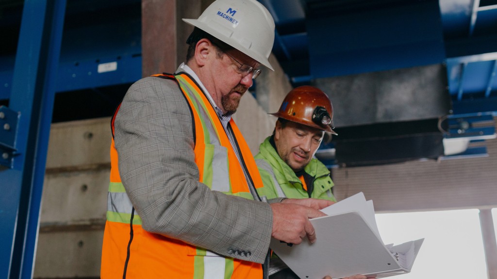 Two workers look at a binder on a job site