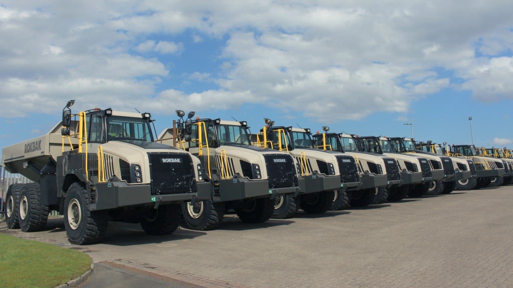 Several articulated haulers are parked in a lot