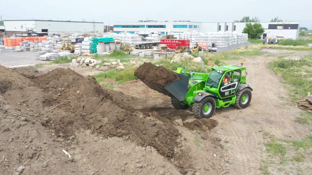 A telehandler using a bucket picks up dirt