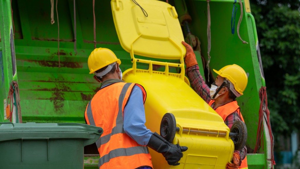 Two people dump the contents of a bin into a collection truck