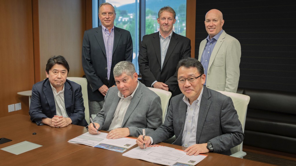 A group of people sign an agreement in an office