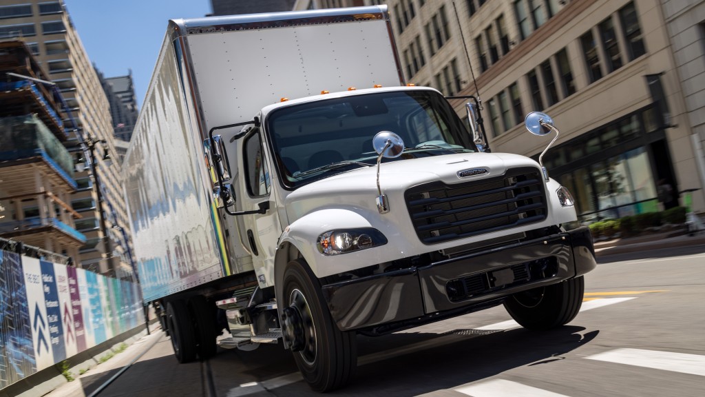 A vocational truck drives down a road