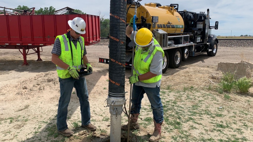 Workers use a vacuum excavator to dig a hole.