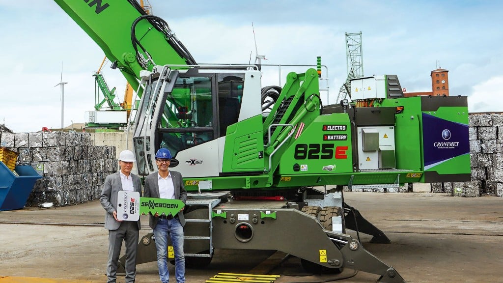 Two people pose for a photo near a material handler