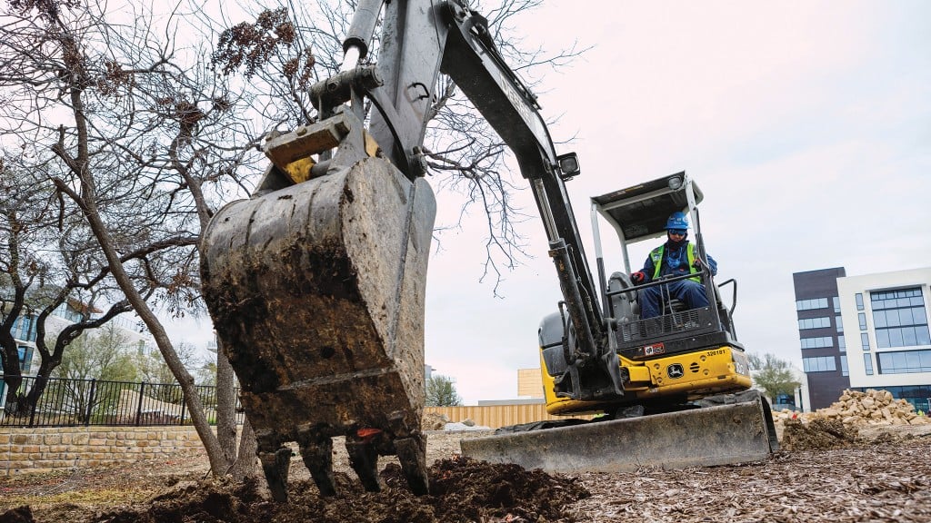 A mini excavator digs dirt on a job site