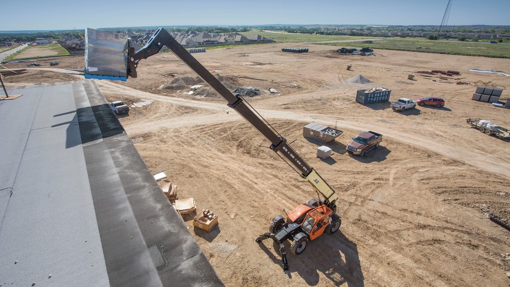 A telehandler lifts a pallet onto a building