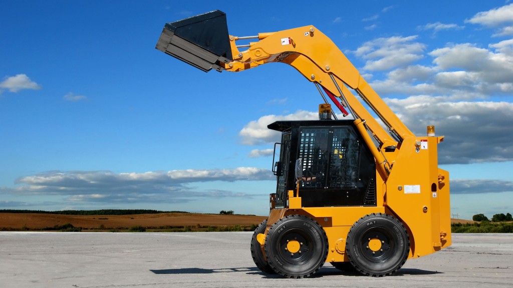 A skid-steer loader drives down a road