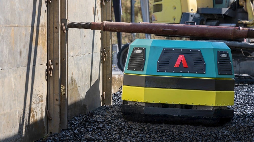 A vibratory compactor travels underneath a pipe