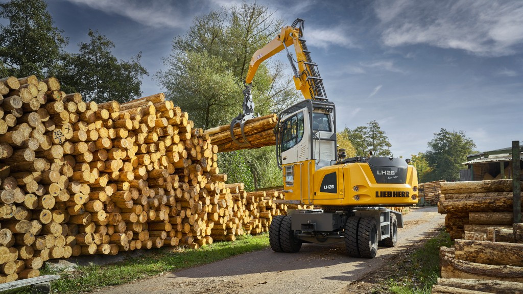 A timber truck lifts a grapple full of logs on a job site
