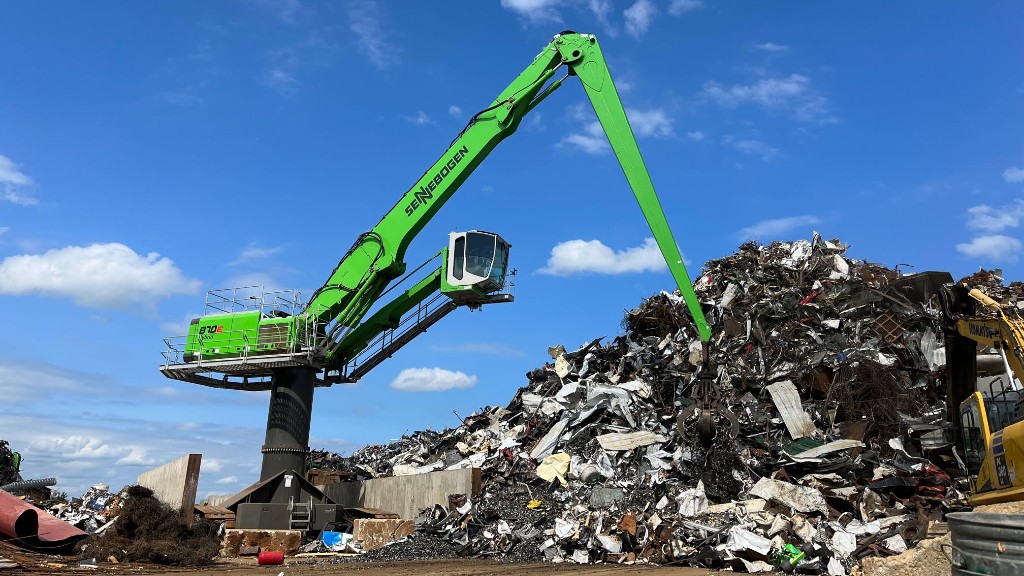 A material handler grabs metal from a large pile