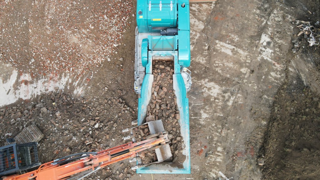 An excavator loads a jaw crusher with material