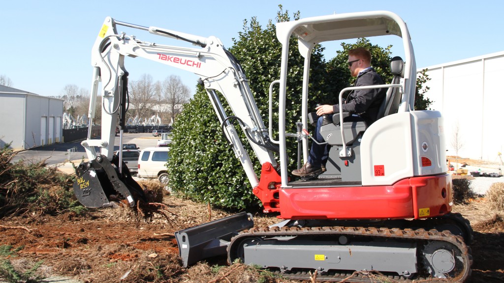 A compact excavator digs roots up on a job site