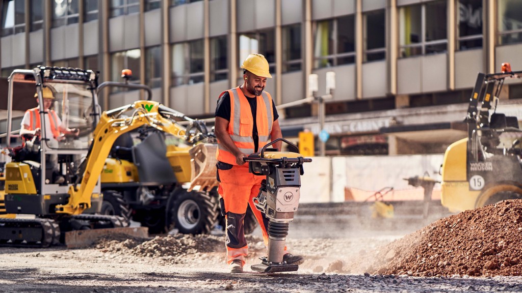 A worker using a vibrating compactor on a job site