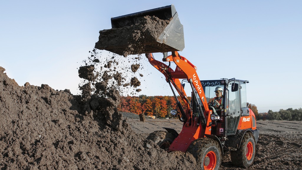 A wheel loader dumps dirt onto a pile