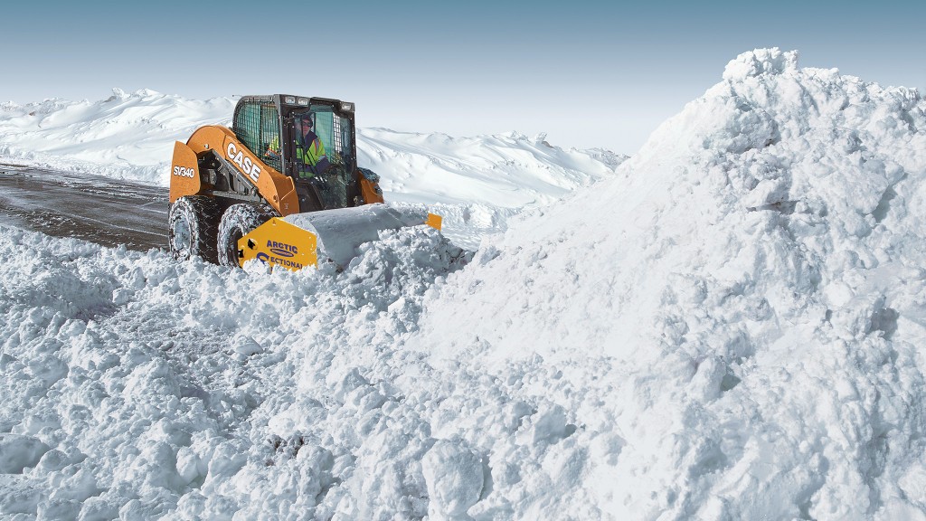 A skid-steer loader pushes snow on a road