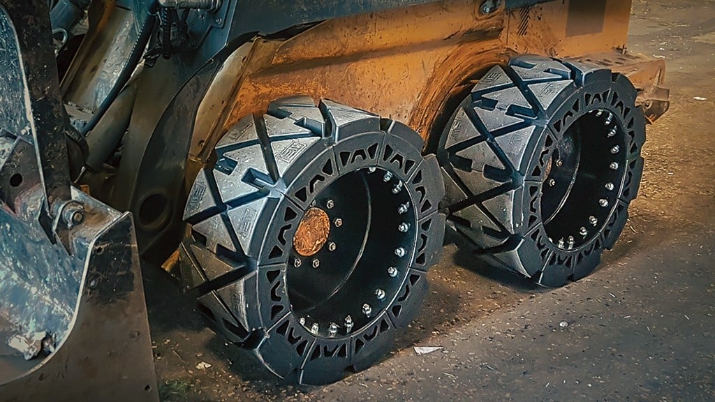 A skid-steer loader uses segmented tires on a job site