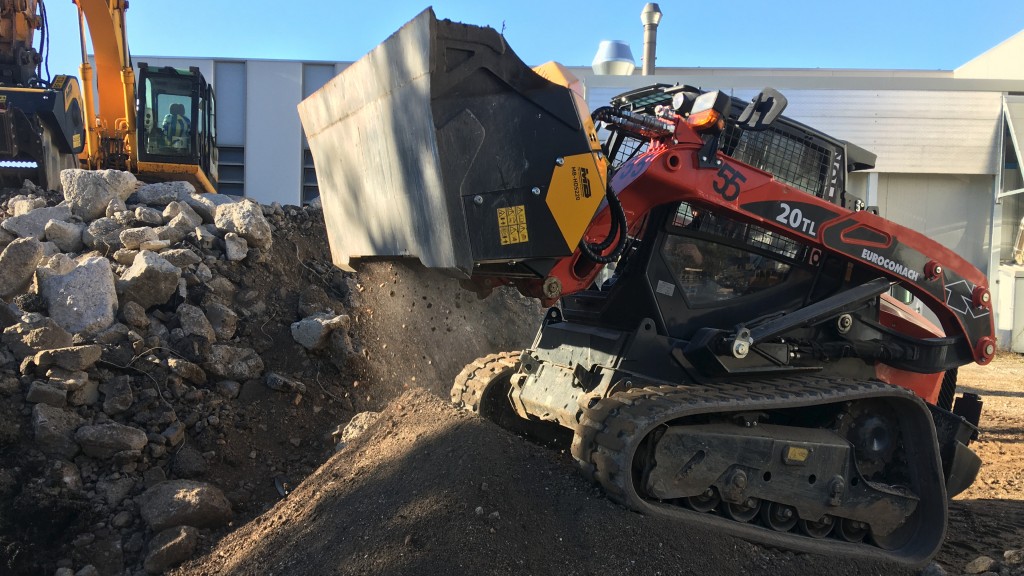 A skid-steer loader uses a padding bucket on a garden job site