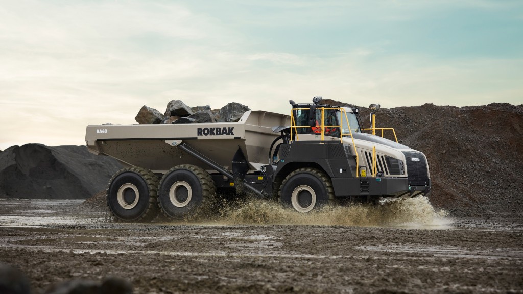 A dump truck drives through a watery rock pit