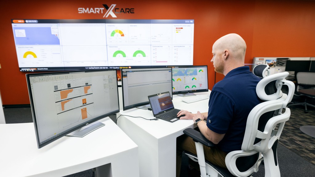 A man monitors several computer screens and works on a laptop