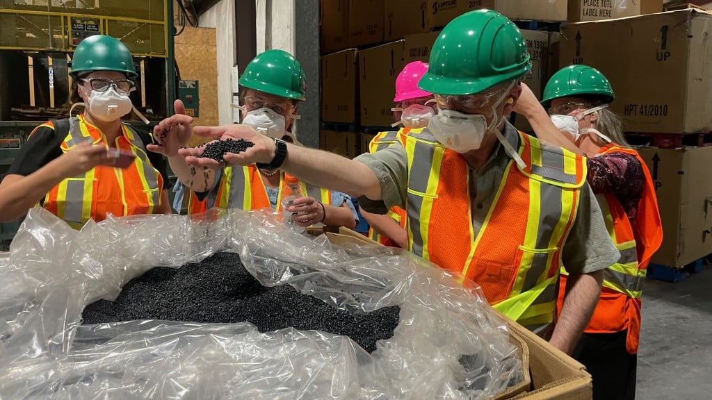 Plastic pellets fall through somebody's hand inside a facility