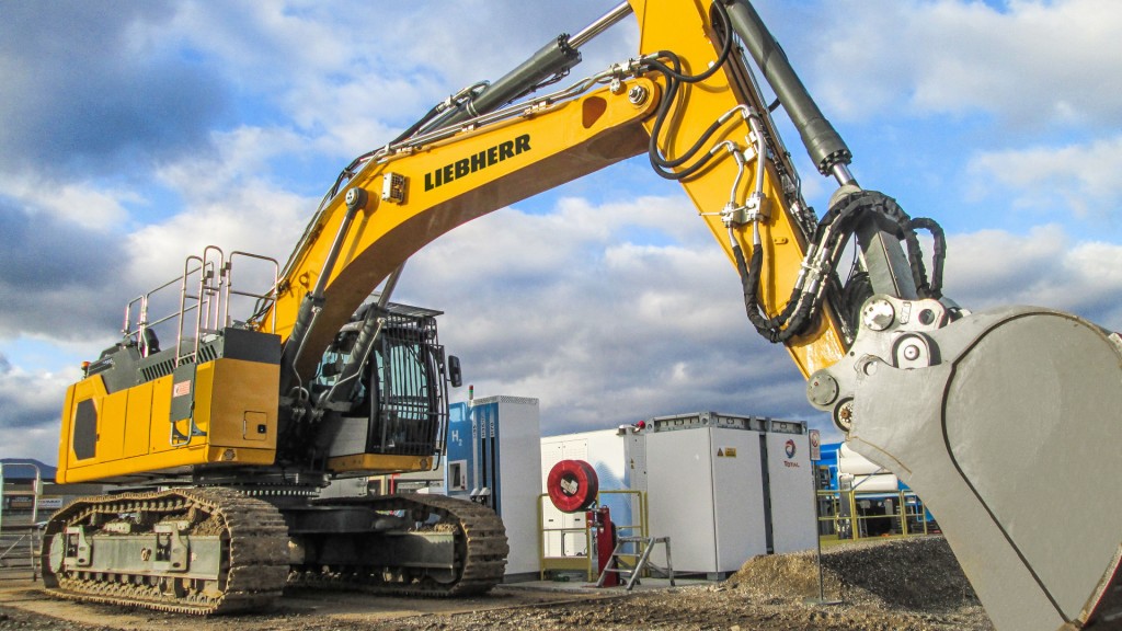 An excavator parked in front of a hydrogen fuelling system.