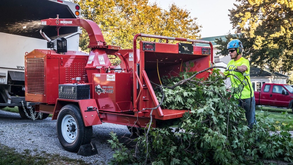 An operator puts tree branches into a brush chipper