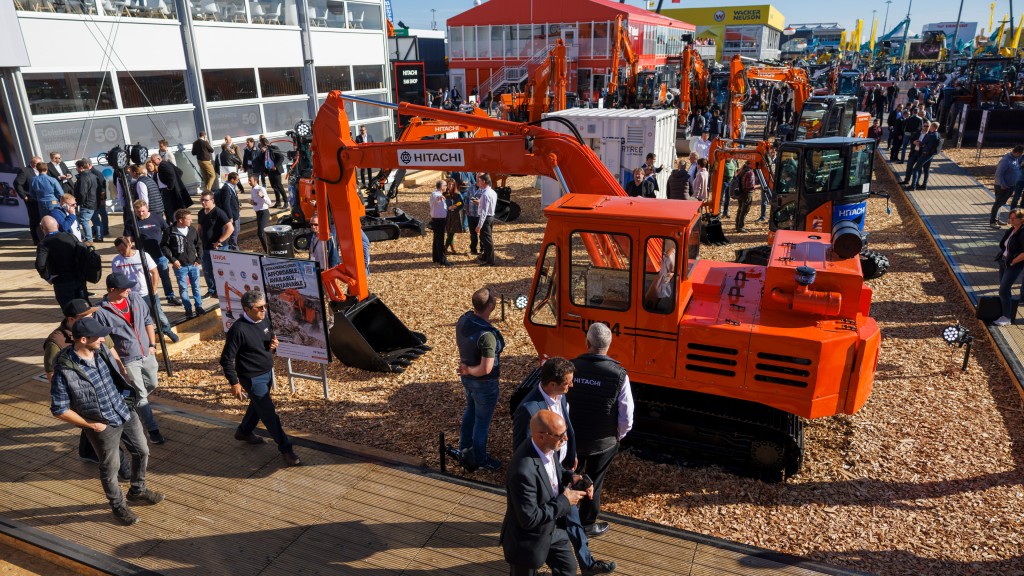 People walk around a restored excavator