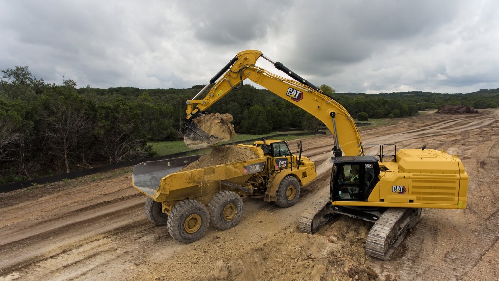 An excavator loads an articulated dump truck on a job site