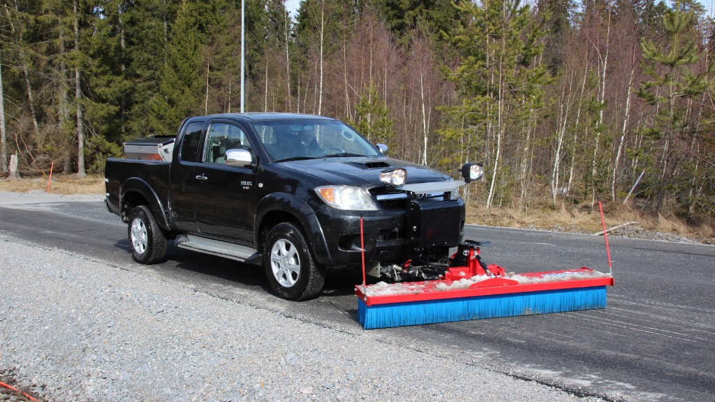 A truck uses a push broom attachment on a road